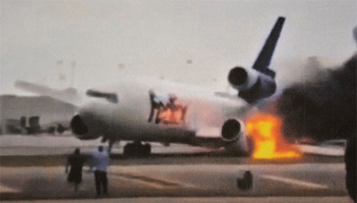 Photo 1. Photograph of the airplane on fire taken a few seconds after the left main landing gear collapsed during landing.