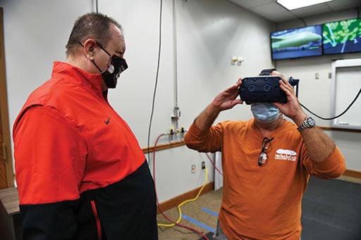 Todd Lavender, 402nd Aircraft Maintenance Group corrosion control process manager, guides Glenn Cross, 588th Aircraft Maintenance Support Squadron aircraft painter, through the virtual reality simulator goggle setup. The aircraft painters are able to get hands-on painting experience for a C-5 or Global Hawk aircraft without going into a hangar to paint on the actual aircraft. U.S. Air Force photo by Joseph Mather.